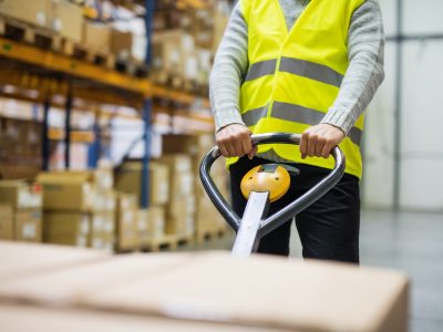 Male warehouse worker pulling a pallet truck.